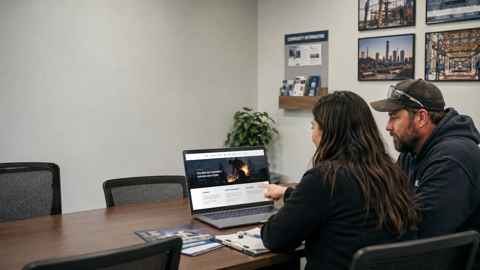 Two people reviewing a local's website on a laptop in the hall's meeting room